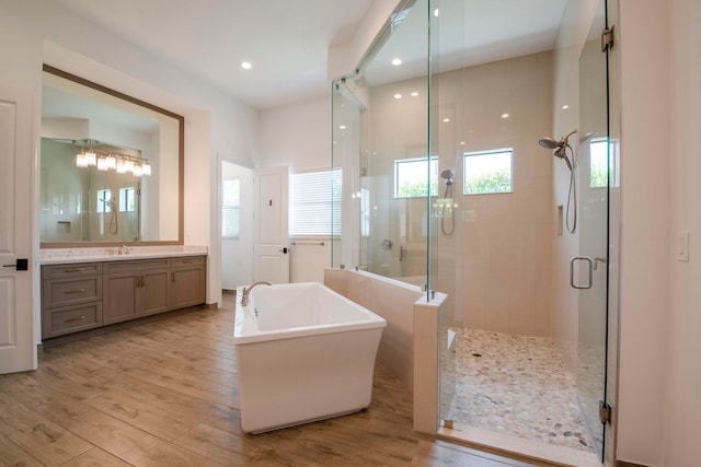 bathroom with shower with separate bathtub, hardwood / wood-style flooring, and vanity