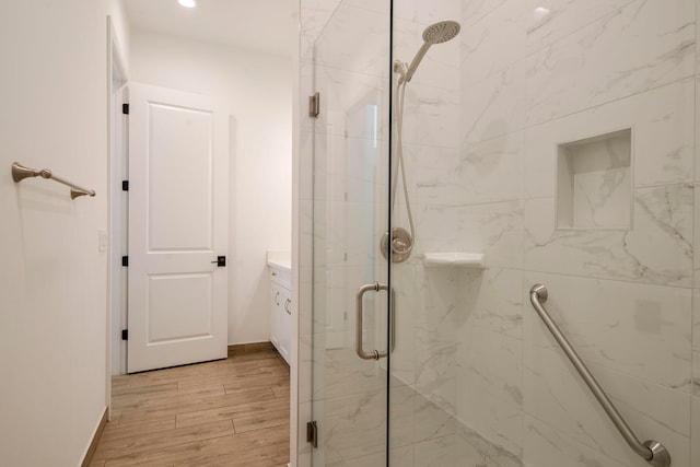 bathroom with walk in shower, vanity, and wood-type flooring