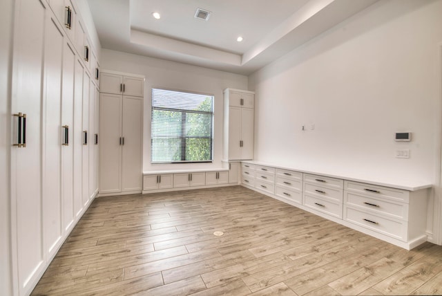 interior space with a tray ceiling and light hardwood / wood-style floors