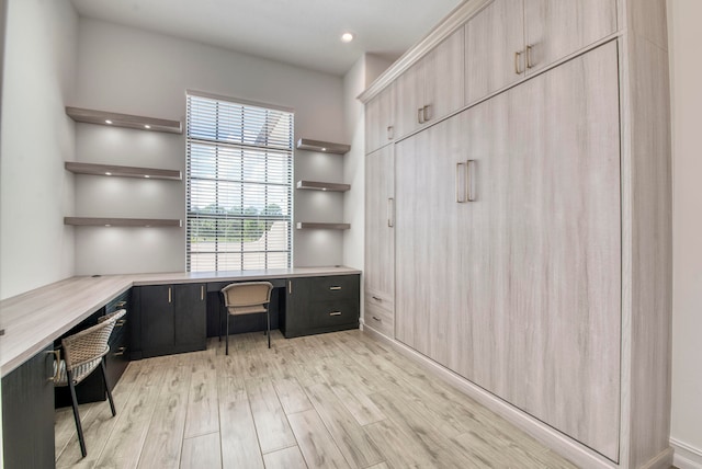 unfurnished office featuring light hardwood / wood-style floors and built in desk