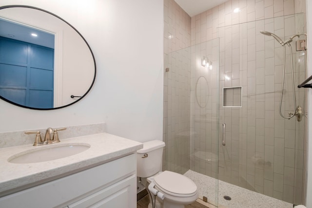 bathroom with walk in shower, vanity, and toilet