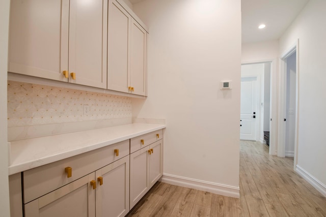 bar with white cabinetry and light hardwood / wood-style flooring