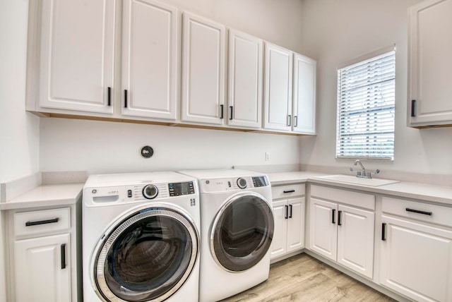 laundry room featuring cabinets, sink, light hardwood / wood-style flooring, and washer and clothes dryer