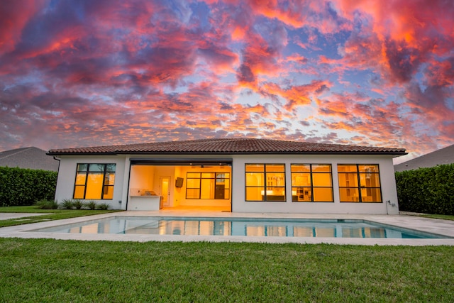 back house at dusk featuring a yard and a patio area