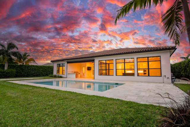 back house at dusk with a patio, a fenced in pool, and a yard