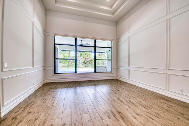 spare room with light hardwood / wood-style flooring and a tray ceiling