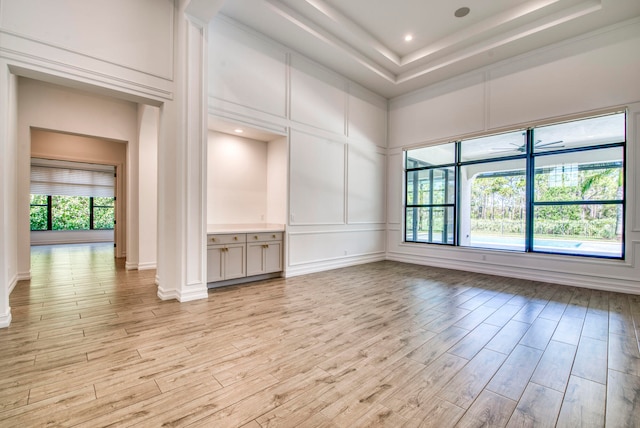 unfurnished room with a raised ceiling, a healthy amount of sunlight, and light hardwood / wood-style flooring