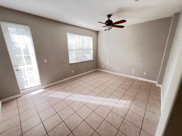 tiled spare room with ceiling fan