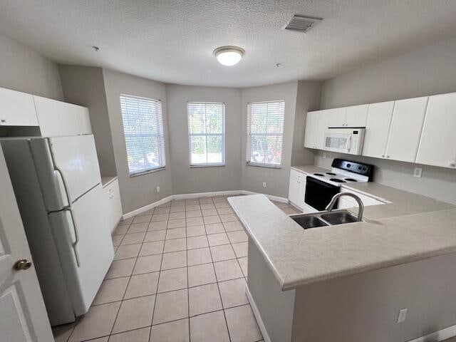 kitchen with sink, light tile patterned floors, white cabinets, a textured ceiling, and white appliances