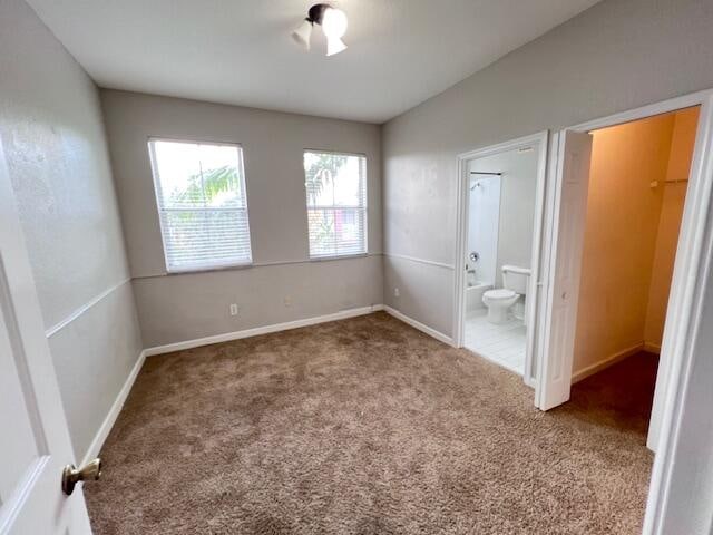 unfurnished bedroom with ensuite bathroom and carpet floors