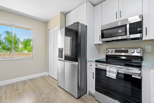 kitchen featuring kitchen peninsula, light hardwood / wood-style flooring, a textured ceiling, appliances with stainless steel finishes, and white cabinetry