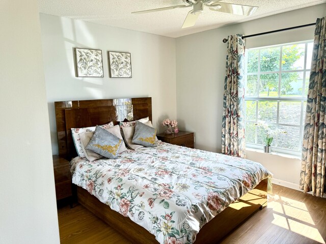 bedroom featuring hardwood / wood-style flooring, a textured ceiling, and ceiling fan