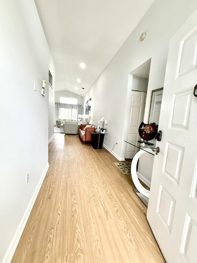 hall featuring lofted ceiling and light hardwood / wood-style floors