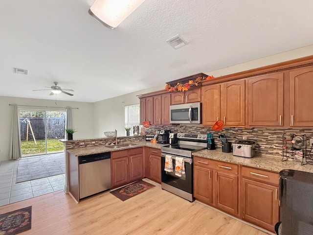 kitchen featuring light hardwood / wood-style floors, sink, kitchen peninsula, appliances with stainless steel finishes, and ceiling fan