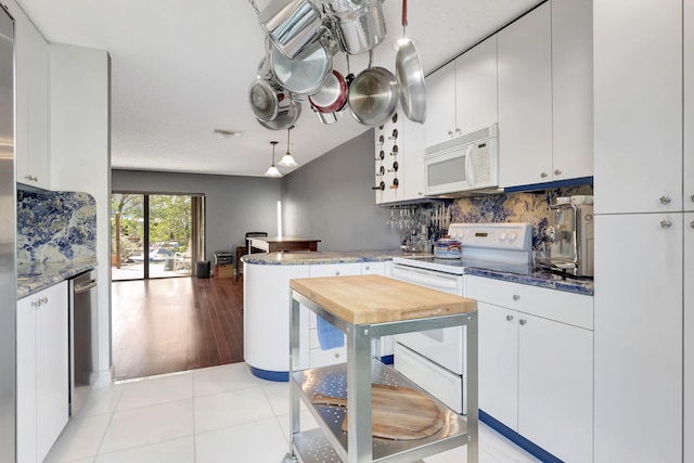 kitchen featuring a peninsula, decorative backsplash, white appliances, and white cabinets