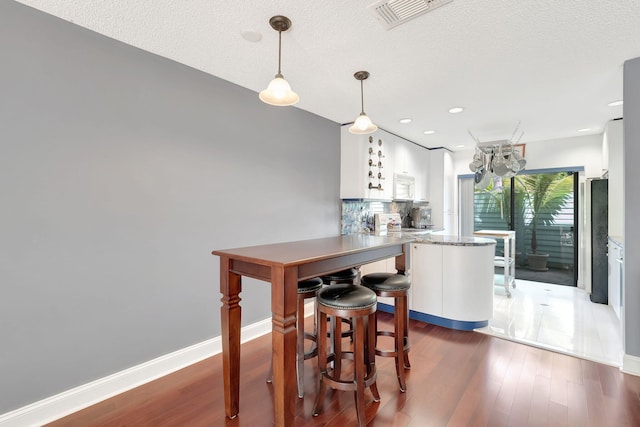 kitchen with visible vents, decorative backsplash, wood finished floors, and white cabinets