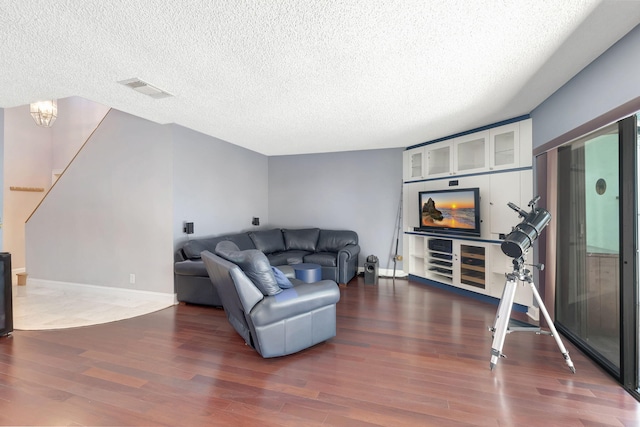 living room featuring visible vents, a textured ceiling, wood finished floors, and stairway