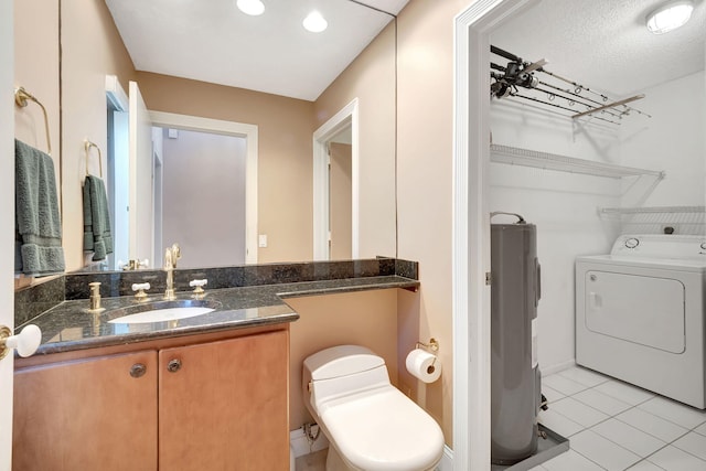 bathroom with tile patterned floors, toilet, washer / dryer, electric water heater, and vanity