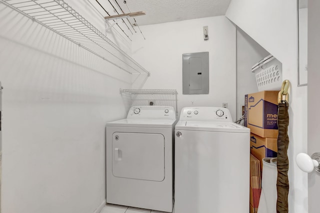 washroom with a textured ceiling, electric panel, and washer and clothes dryer