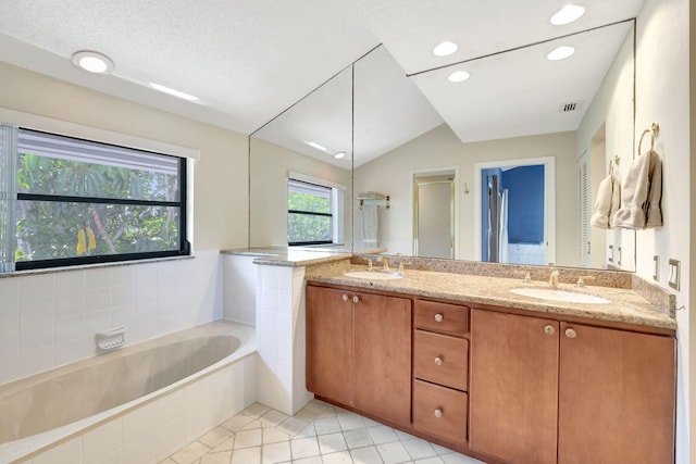 bathroom featuring plus walk in shower, a textured ceiling, vaulted ceiling, vanity, and tile patterned flooring