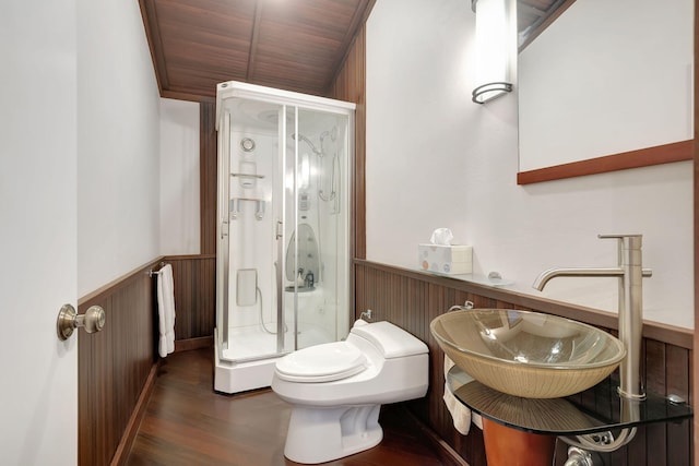 bathroom featuring wood walls, sink, an enclosed shower, toilet, and hardwood / wood-style flooring