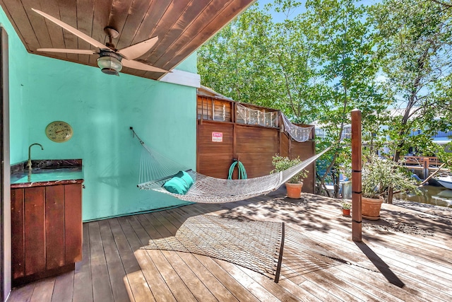 wooden deck with a water view, ceiling fan, and sink