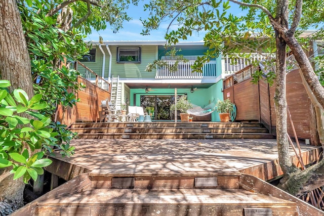 rear view of property with stairs, ceiling fan, a wooden deck, and a balcony