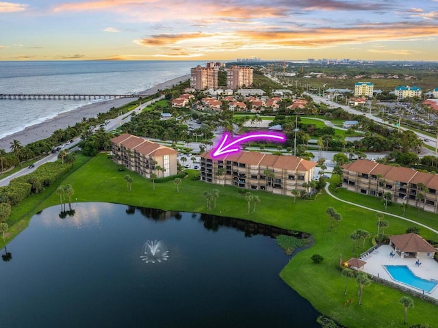 aerial view at dusk featuring a water view