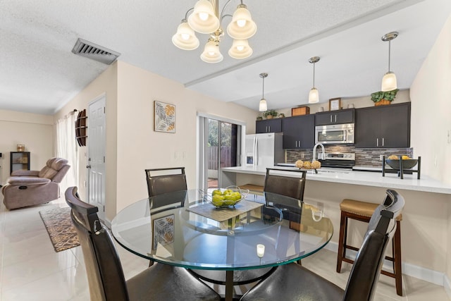 dining space featuring a textured ceiling, light tile patterned floors, and a chandelier