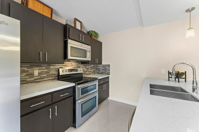 kitchen with hanging light fixtures, sink, appliances with stainless steel finishes, a textured ceiling, and tasteful backsplash