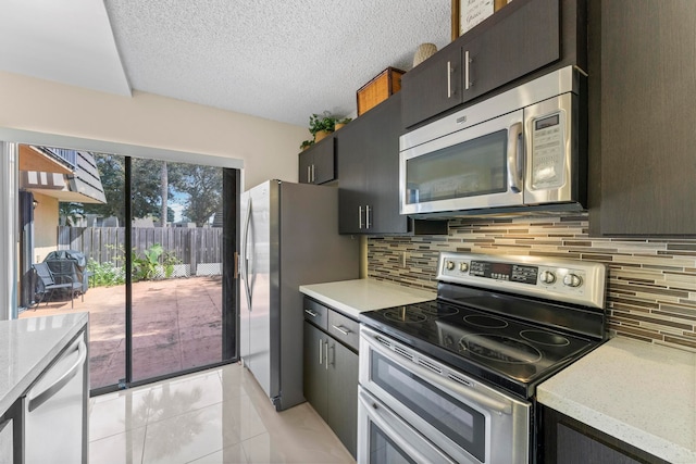 kitchen featuring tasteful backsplash, appliances with stainless steel finishes, a textured ceiling, light stone counters, and light tile patterned floors