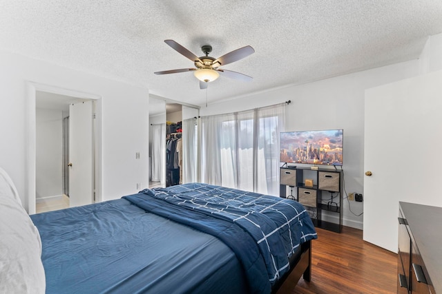 bedroom with dark wood-type flooring, ceiling fan, a closet, and a textured ceiling