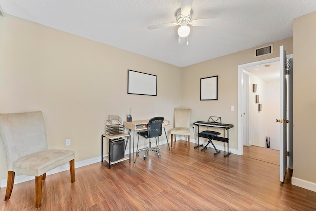 sitting room with a textured ceiling, hardwood / wood-style flooring, and ceiling fan