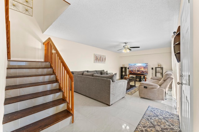 living room with a textured ceiling, light tile patterned floors, and ceiling fan