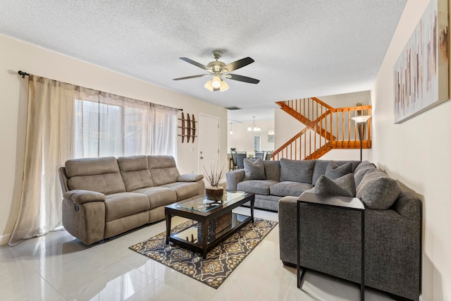 living room with a textured ceiling, light tile patterned floors, and ceiling fan with notable chandelier