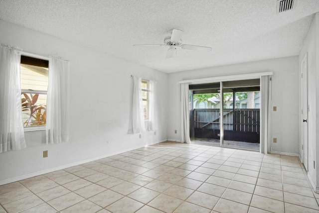 tiled empty room with ceiling fan and a textured ceiling