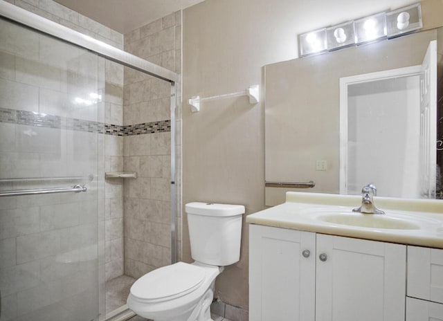 bathroom featuring toilet, vanity, and a stall shower