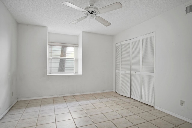 unfurnished bedroom featuring a closet, a textured ceiling, light tile patterned floors, and ceiling fan