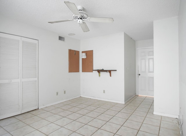 interior space with a closet, ceiling fan, a textured ceiling, and light tile patterned floors