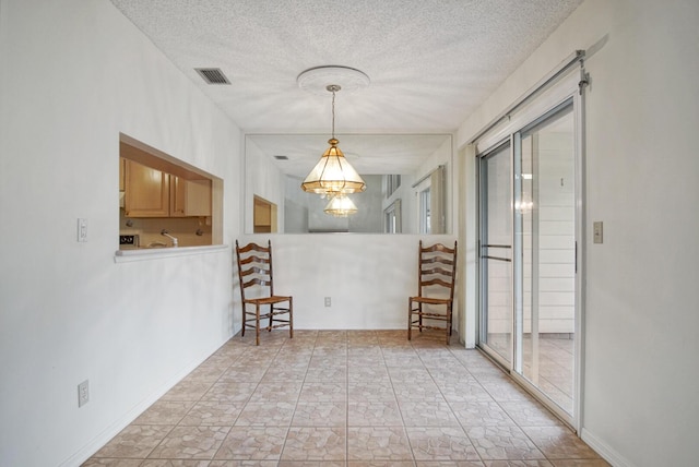 unfurnished room featuring a chandelier, a textured ceiling, and visible vents