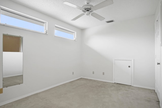 unfurnished room featuring ceiling fan, a textured ceiling, and light colored carpet