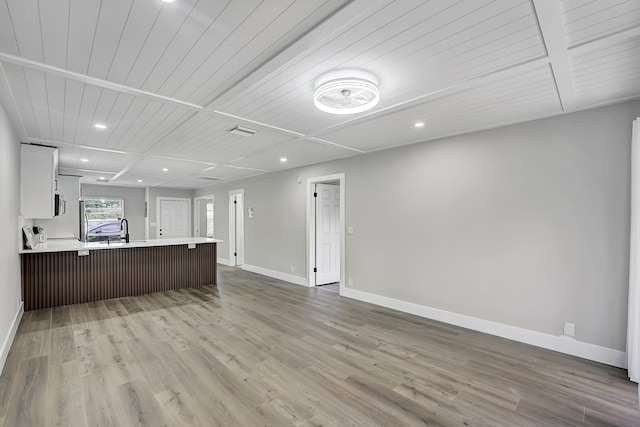 unfurnished living room featuring wood ceiling, wood-type flooring, and sink