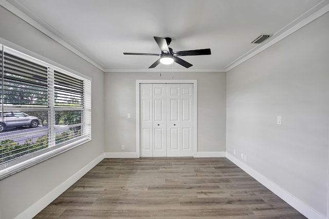 unfurnished bedroom featuring a closet, ornamental molding, light wood-type flooring, and ceiling fan