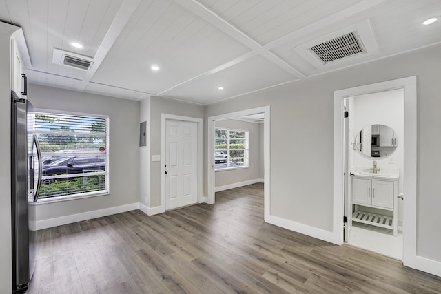 unfurnished room with beam ceiling, sink, and hardwood / wood-style floors