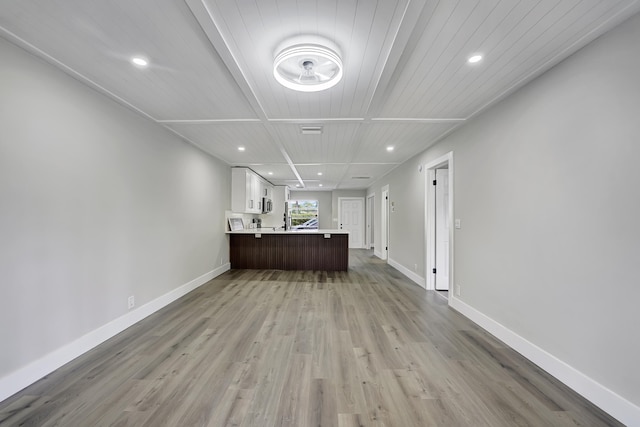 interior space featuring wood ceiling, light wood-type flooring, and white cabinets