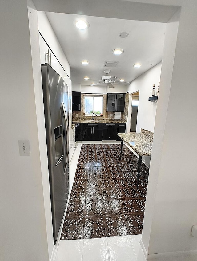 kitchen featuring stainless steel fridge, black dishwasher, ceiling fan, tile patterned flooring, and decorative backsplash