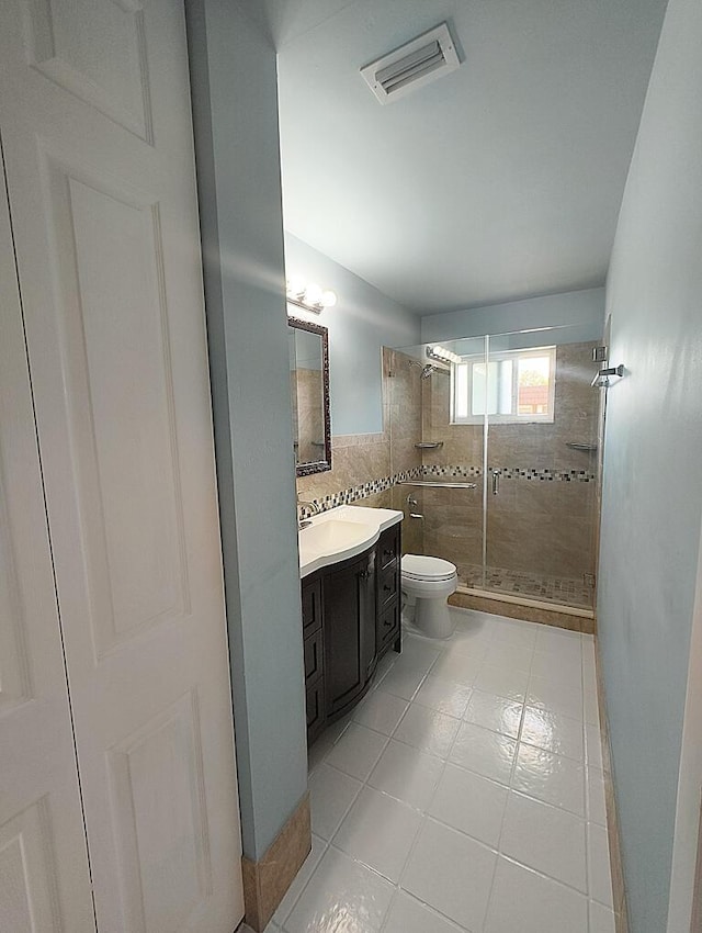 bathroom featuring vanity, tiled shower, tile walls, and toilet