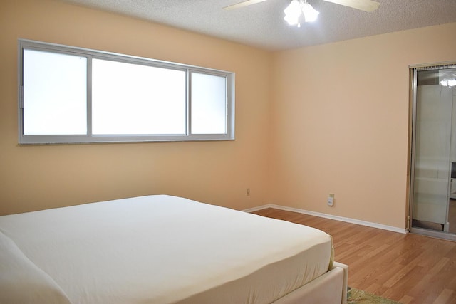 bedroom with hardwood / wood-style floors, a textured ceiling, and ceiling fan