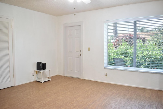 unfurnished room featuring ceiling fan, a textured ceiling, and light wood-type flooring