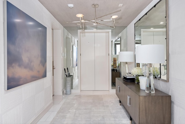 hall featuring a chandelier, a textured ceiling, and light tile patterned floors